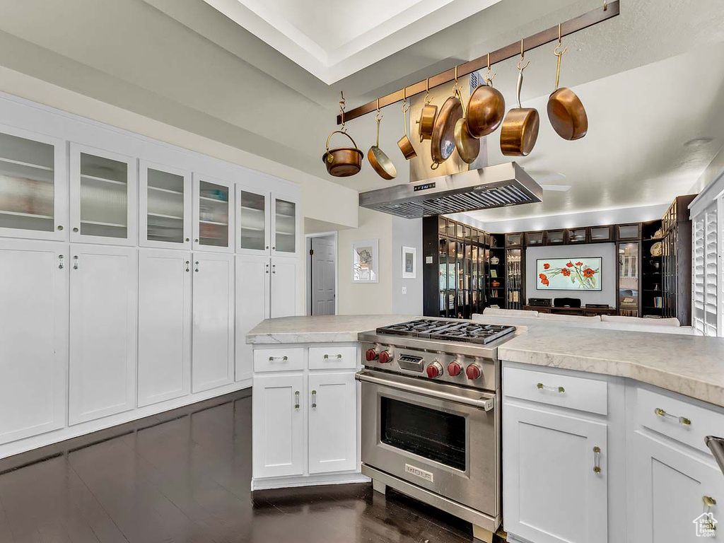 Kitchen featuring light countertops, white cabinets, glass insert cabinets, and premium stove