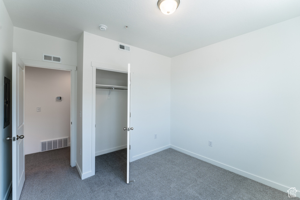 Unfurnished bedroom with visible vents, carpet, and a closet