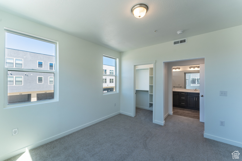 Unfurnished bedroom featuring visible vents, baseboards, carpet floors, a closet, and a spacious closet