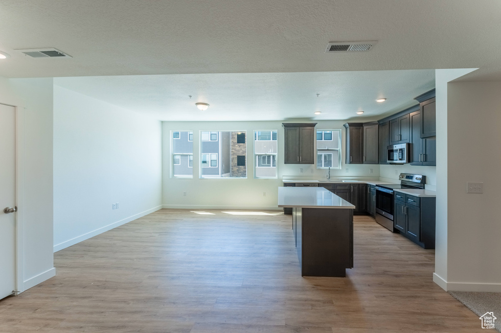 Kitchen with a kitchen island, baseboards, appliances with stainless steel finishes, and visible vents