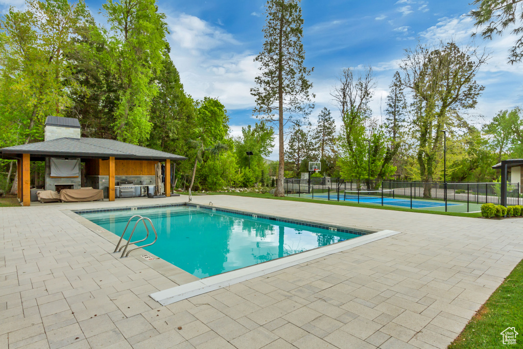 View of swimming pool featuring fence, a fenced in pool, a tennis court, and a gazebo