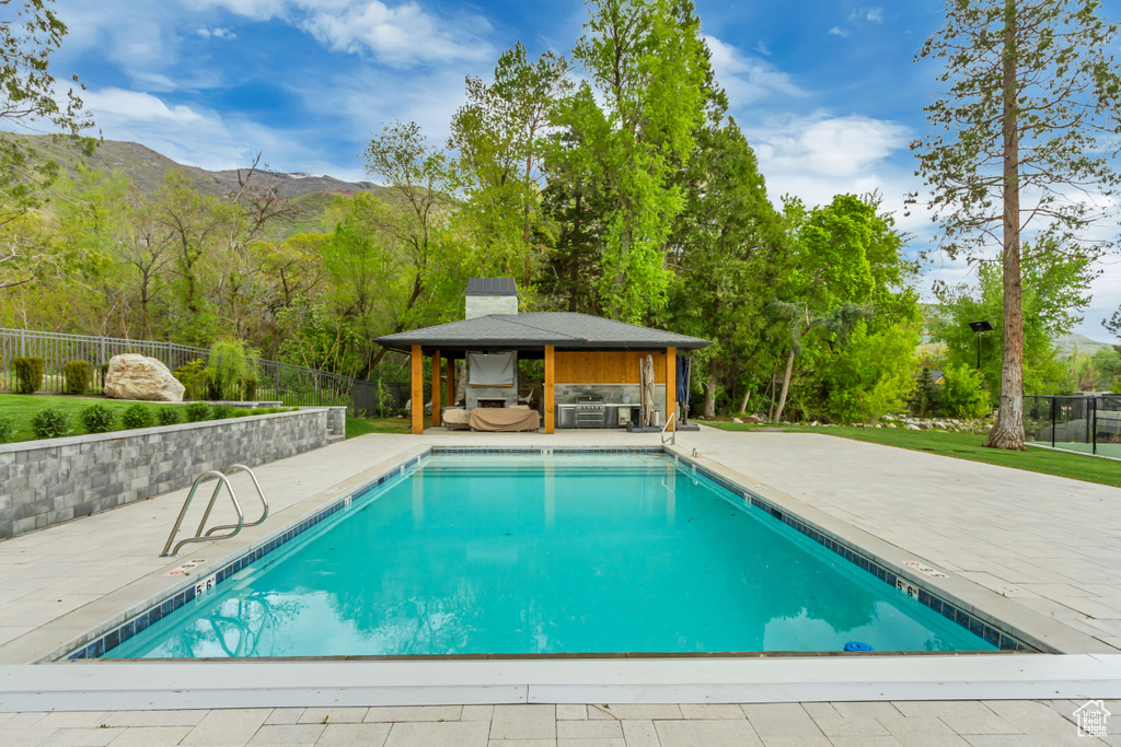 Community pool with a gazebo, a mountain view, fence, and a patio