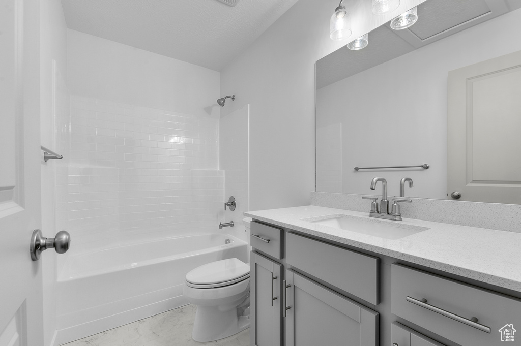 Bathroom featuring vanity, shower / bathtub combination, toilet, and marble finish floor