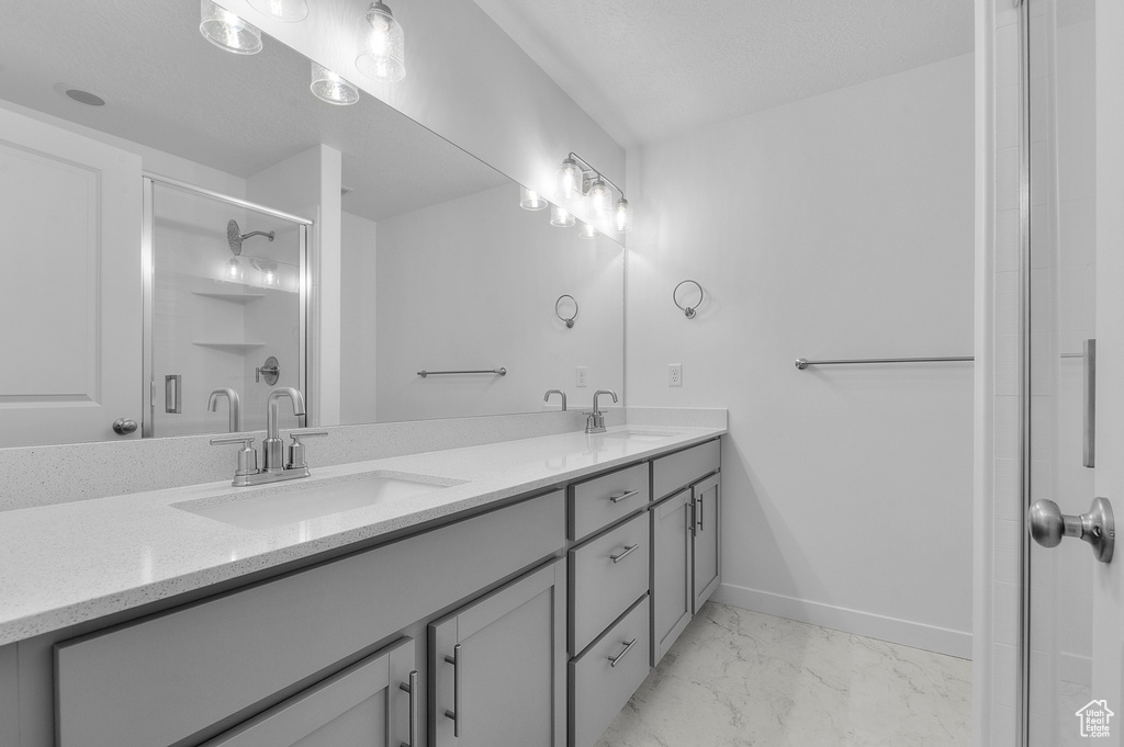 Full bathroom featuring a sink, a stall shower, double vanity, and marble finish floor