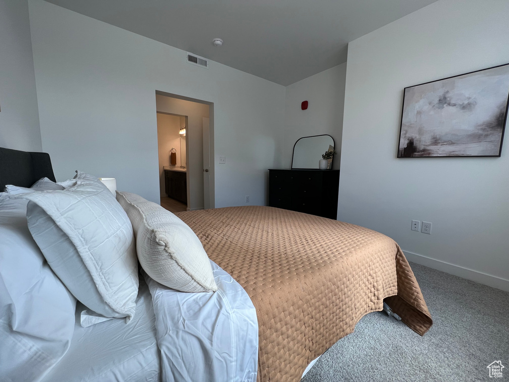 Carpeted bedroom with visible vents and ensuite bathroom