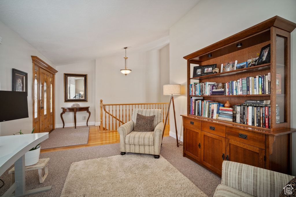 Living area featuring lofted ceiling, light carpet, baseboards, and an upstairs landing