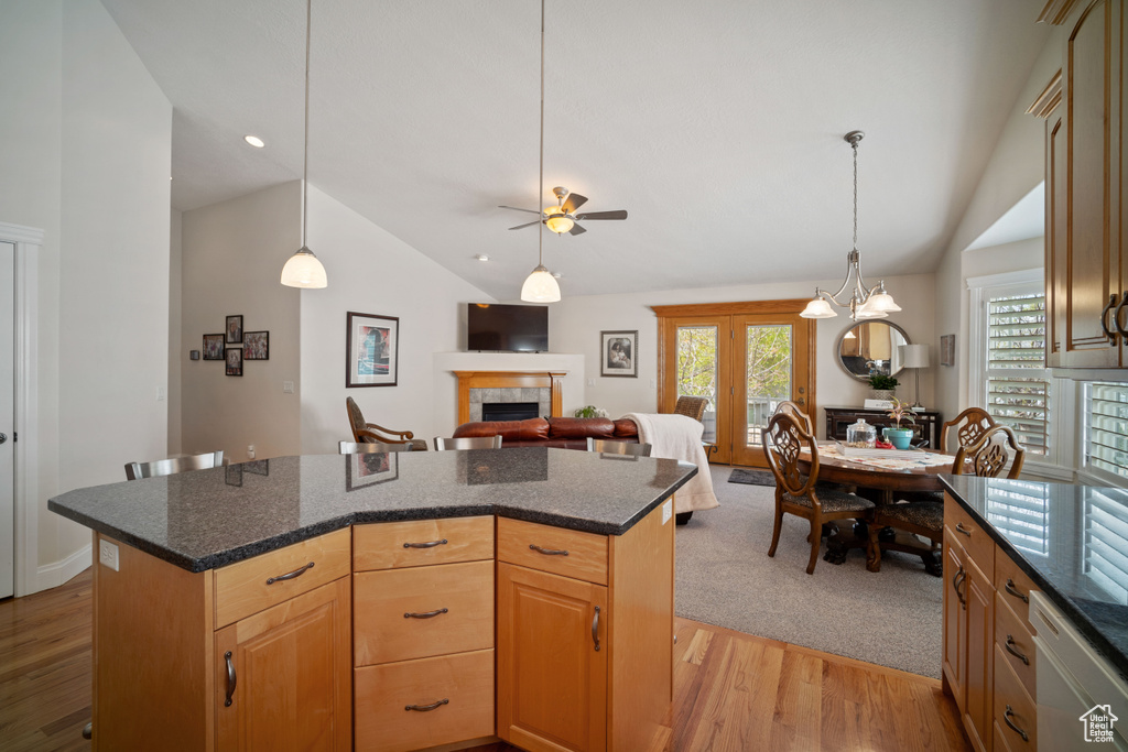 Kitchen featuring lofted ceiling, white dishwasher, a center island, a fireplace, and light wood-style flooring