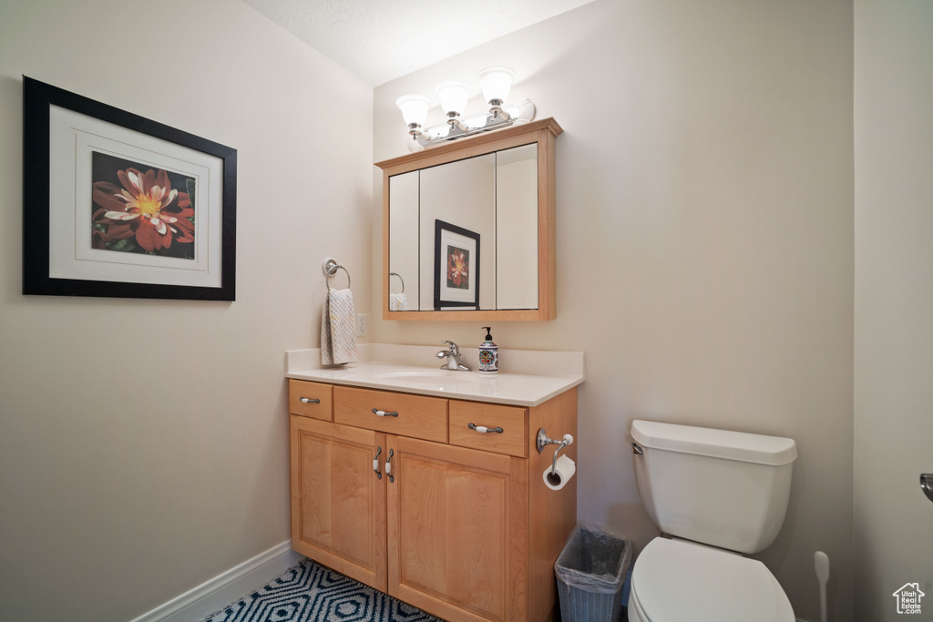 Half bathroom with toilet, vanity, and baseboards