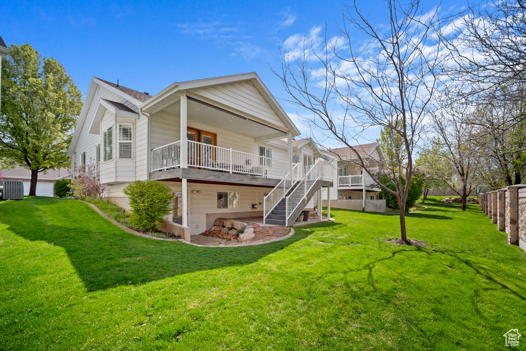Back of property with central AC, a wooden deck, a yard, and stairs