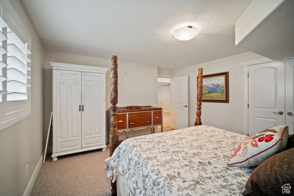 Carpeted bedroom featuring baseboards, a textured ceiling, and a closet
