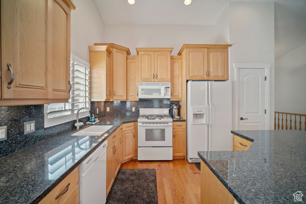 Kitchen with light brown cabinets, a sink, white appliances, and light wood-type flooring