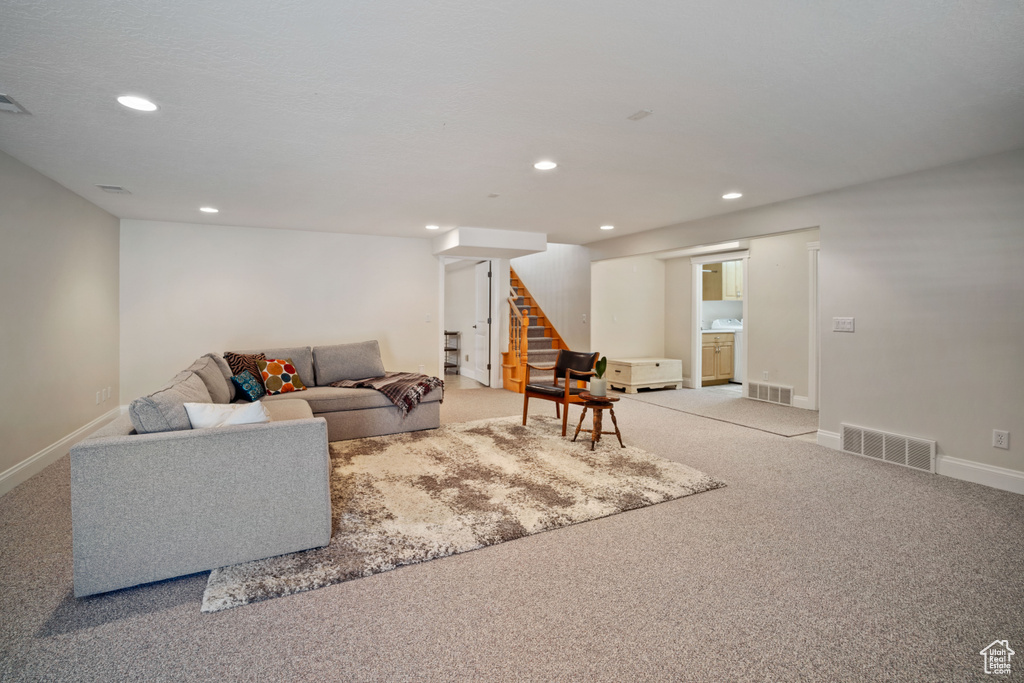 Living area with light carpet, visible vents, recessed lighting, and stairs