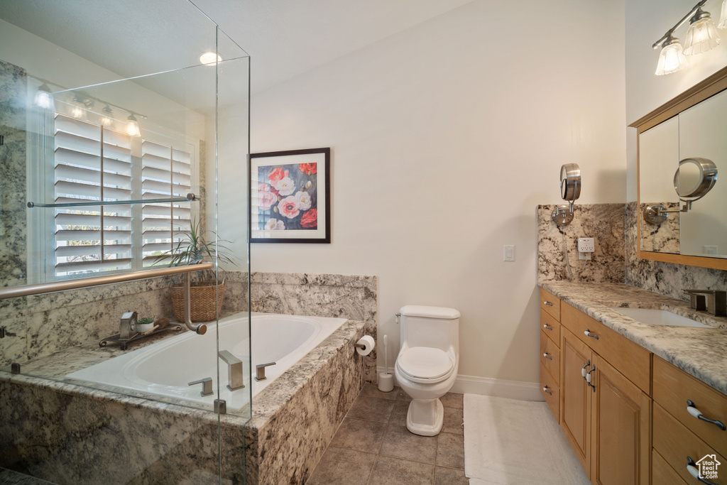Full bathroom with a garden tub, tile patterned floors, vanity, baseboards, and toilet