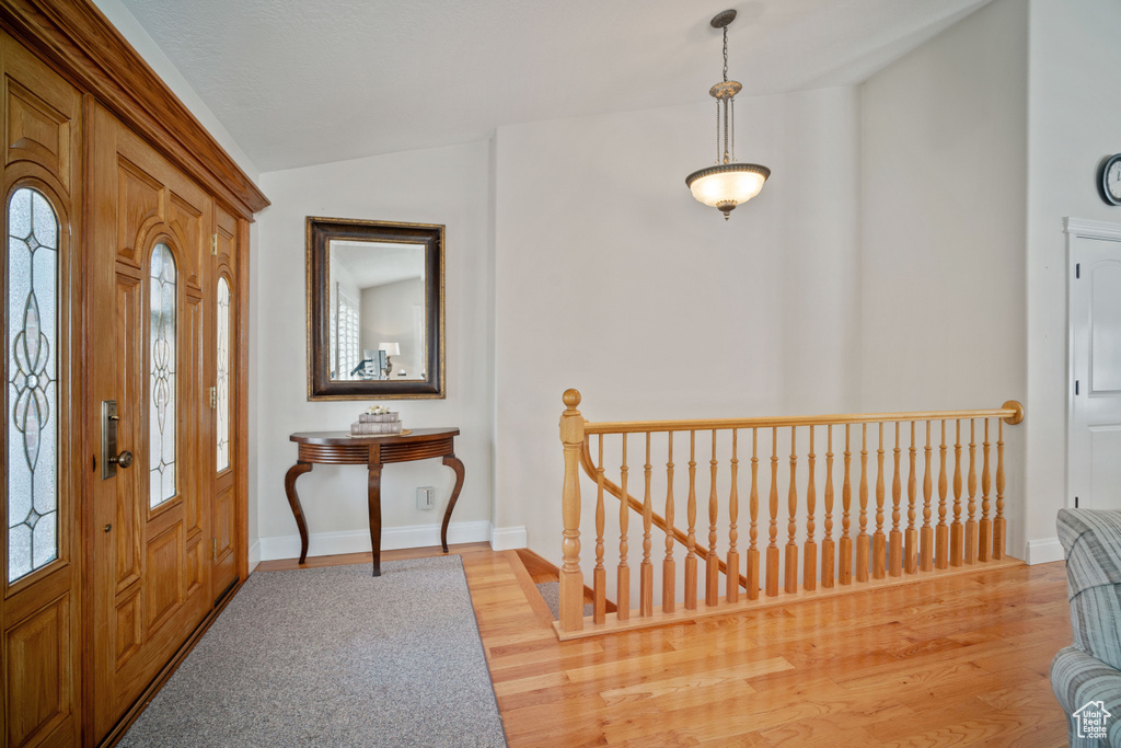 Entryway with vaulted ceiling, light wood finished floors, and baseboards