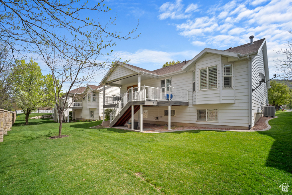 Rear view of property with cooling unit, a lawn, a wooden deck, and stairway