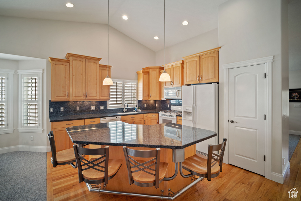 Kitchen featuring a center island, a sink, decorative backsplash, white appliances, and high vaulted ceiling