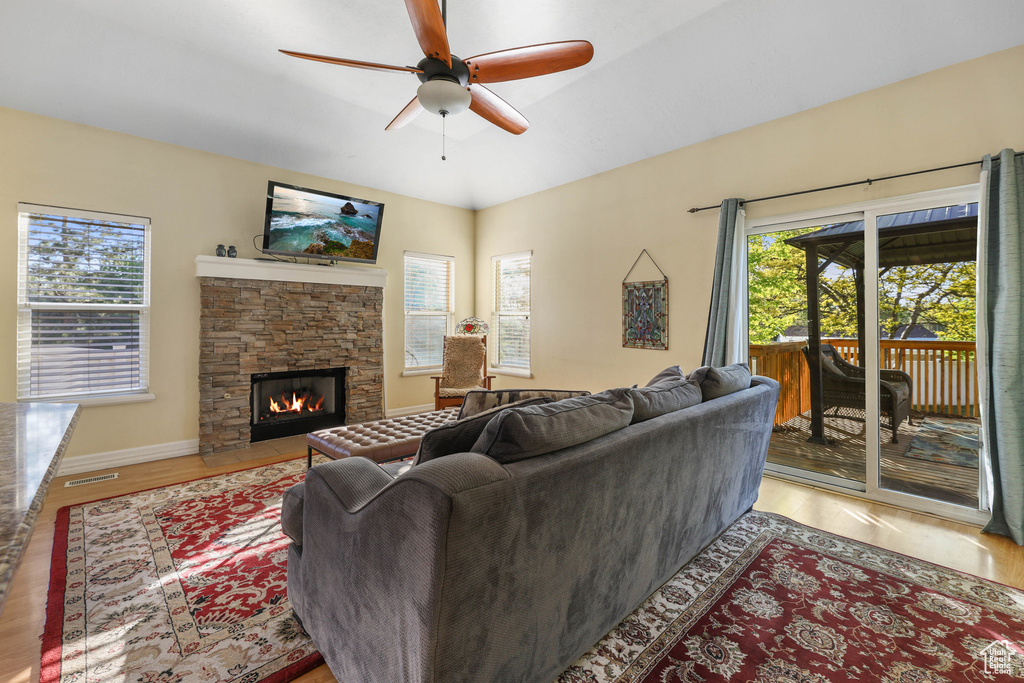 Living room featuring visible vents, wood finished floors, a fireplace, baseboards, and ceiling fan