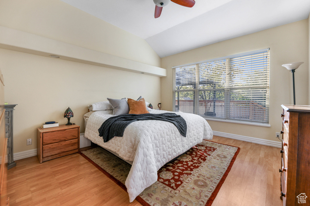 Bedroom featuring a ceiling fan, baseboards, vaulted ceiling, and light wood-style flooring