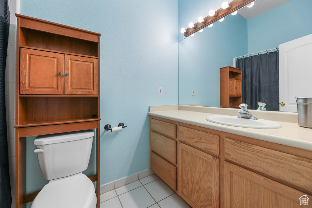 Full bath featuring tile patterned flooring, vanity, toilet, baseboards, and a shower with shower curtain