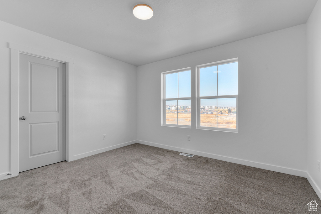 Carpeted empty room with baseboards and visible vents