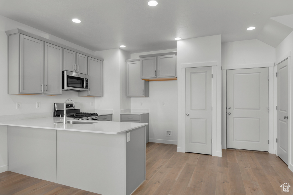 Kitchen featuring light wood-type flooring, gray cabinetry, a peninsula, stainless steel appliances, and recessed lighting