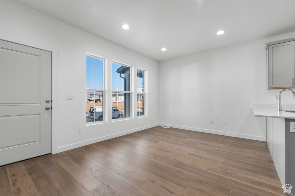 Unfurnished dining area featuring a sink, baseboards, recessed lighting, and wood finished floors