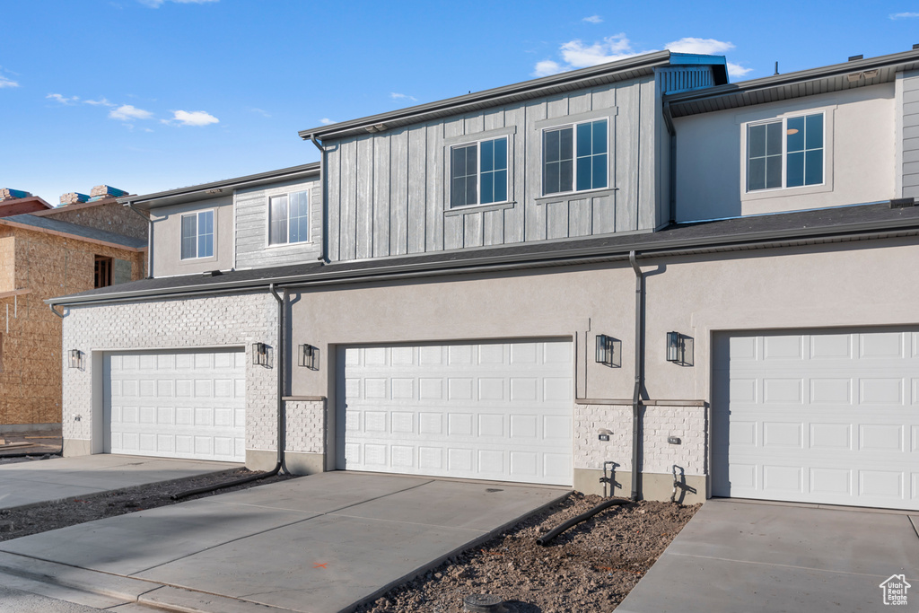 View of property featuring board and batten siding, an attached garage, concrete driveway, and stucco siding