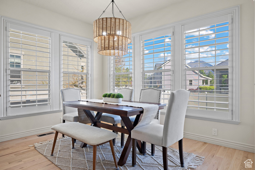 Dining space featuring baseboards, wood finished floors, visible vents, and an inviting chandelier
