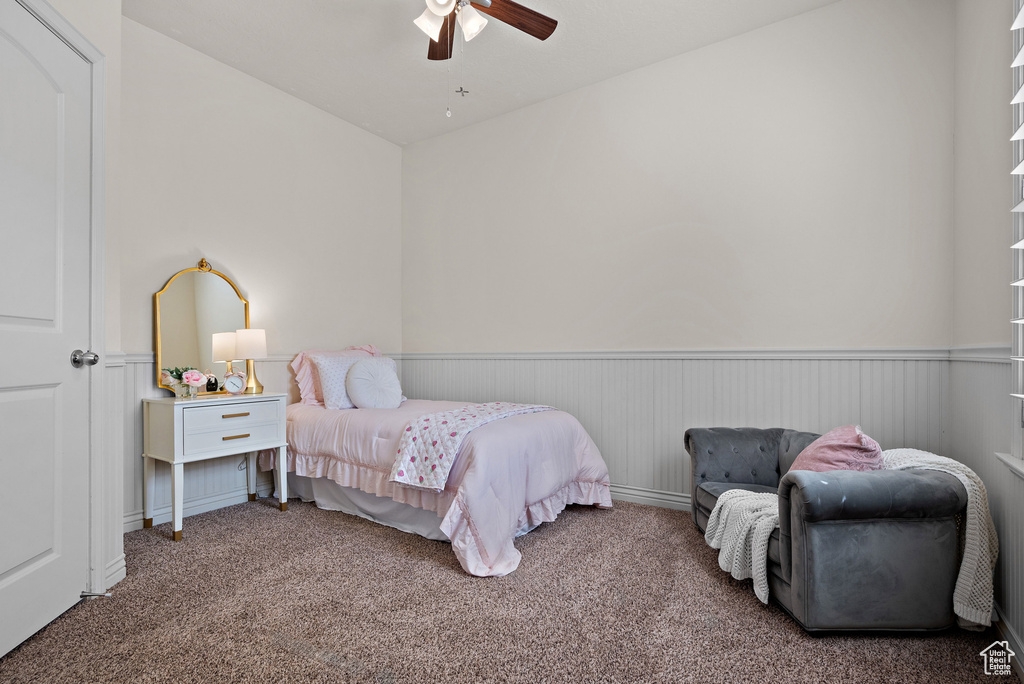 Bedroom featuring carpet floors, a ceiling fan, and a wainscoted wall