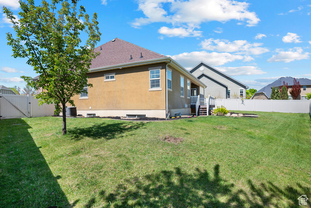 Rear view of property featuring a fenced backyard, stucco siding, a gate, central air condition unit, and a yard