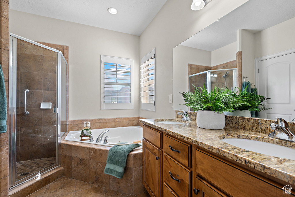 Bathroom featuring double vanity, a sink, a garden tub, and a stall shower