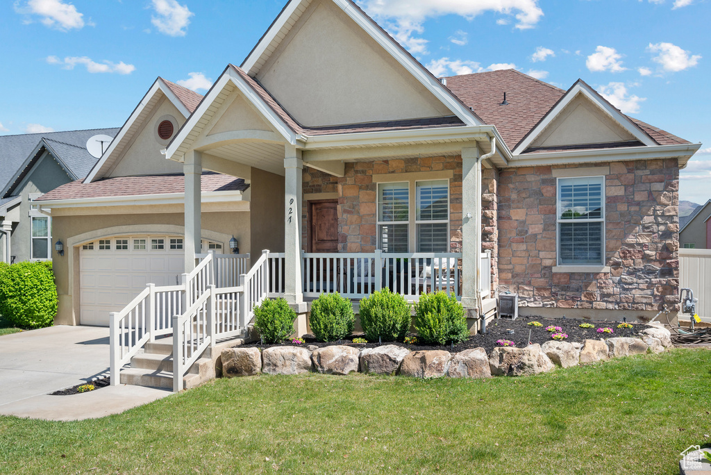 View of front of property with covered porch, stucco siding, a shingled roof, an attached garage, and driveway