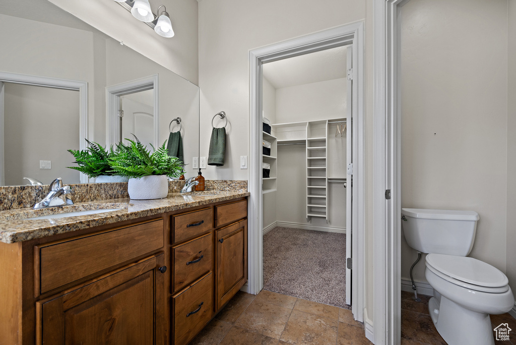 Full bath featuring double vanity, toilet, a walk in closet, and a sink