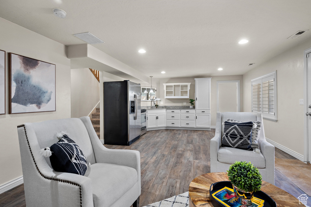 Living room with recessed lighting, visible vents, wood finished floors, and stairway