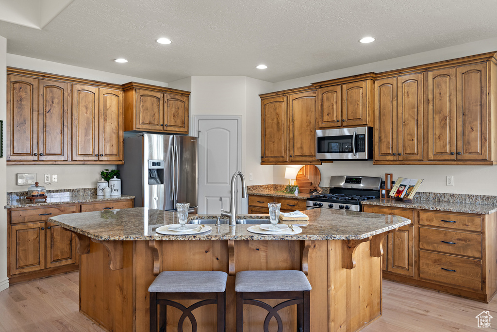 Kitchen featuring appliances with stainless steel finishes, a kitchen breakfast bar, and light wood-type flooring