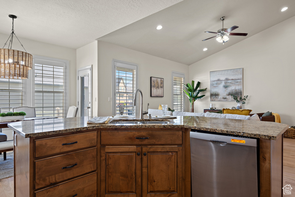Kitchen featuring stainless steel dishwasher, open floor plan, plenty of natural light, a sink, and light wood finished floors