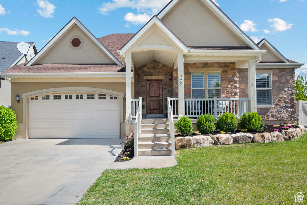 View of front of house featuring an attached garage, stucco siding, driveway, and stone siding