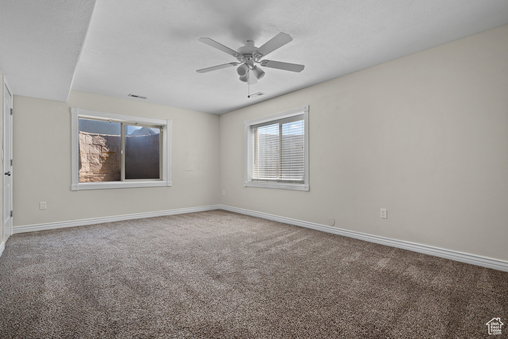 Spare room featuring baseboards, carpet flooring, a ceiling fan, and visible vents