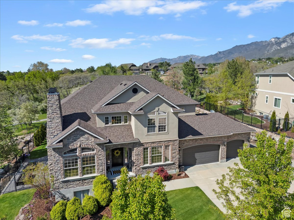 View of front of property with a garage, fence, stucco siding, and stone siding