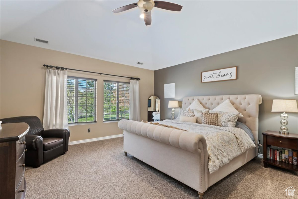 Bedroom featuring a ceiling fan, visible vents, vaulted ceiling, baseboards, and carpet