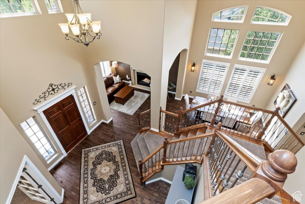 Entryway featuring an inviting chandelier, a towering ceiling, wood finished floors, baseboards, and arched walkways
