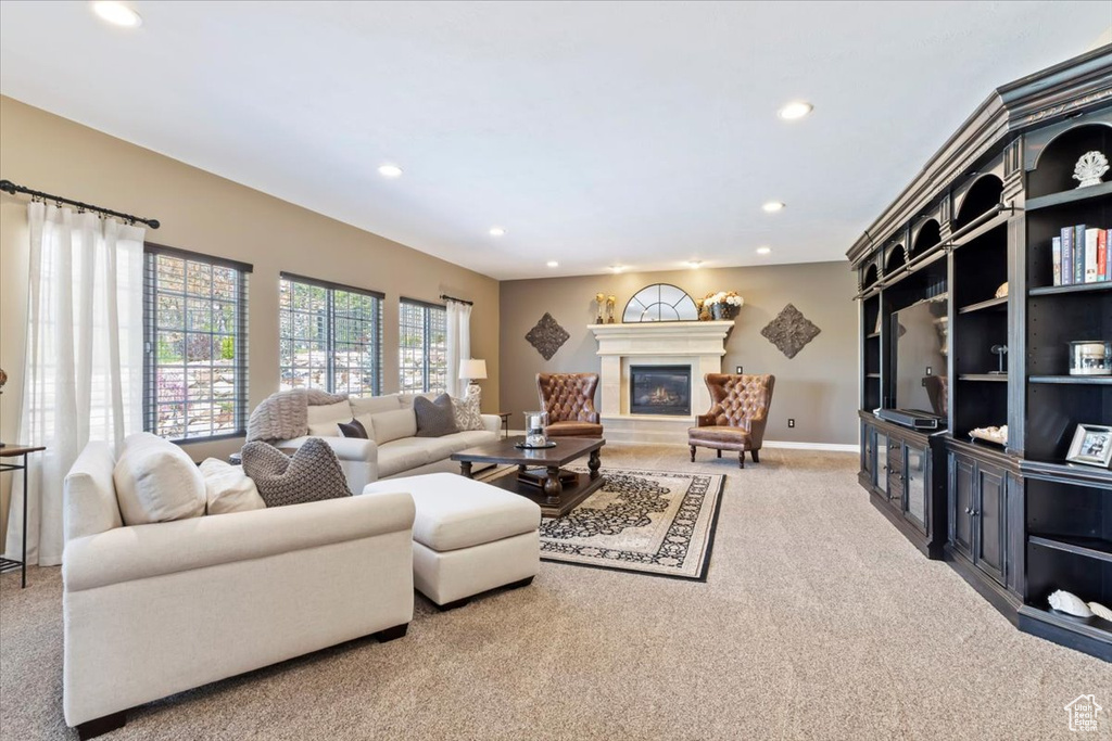 Carpeted living area featuring a glass covered fireplace, baseboards, and recessed lighting