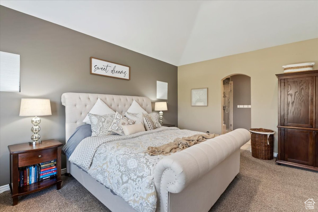 Carpeted bedroom featuring arched walkways and vaulted ceiling
