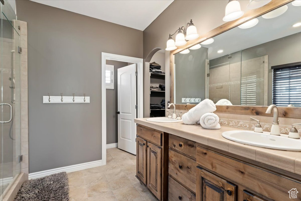 Bathroom featuring double vanity, a sink, and a stall shower
