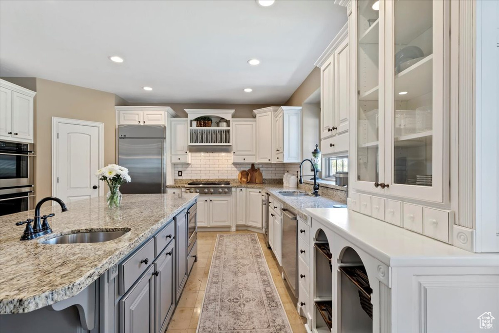 Kitchen with white cabinets, stainless steel appliances, gray cabinets, and a sink