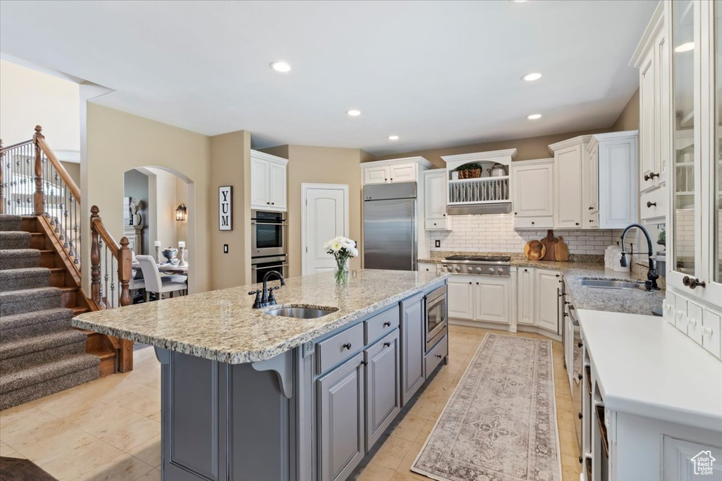 Kitchen with built in appliances, gray cabinets, a sink, and white cabinets