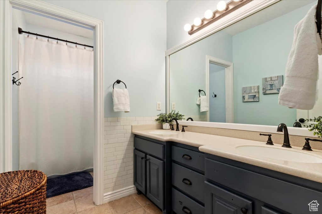 Bathroom featuring a sink, tile walls, tile patterned floors, and double vanity