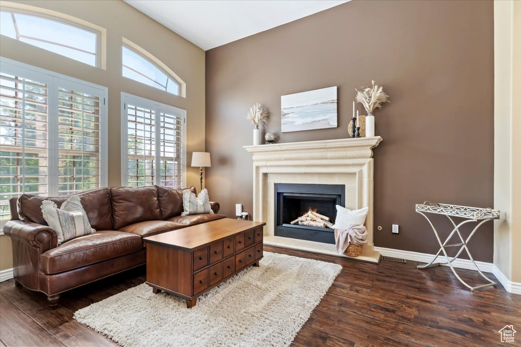 Living area with baseboards, a lit fireplace, and dark wood-style flooring