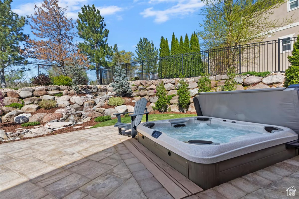 View of patio with a covered hot tub and fence