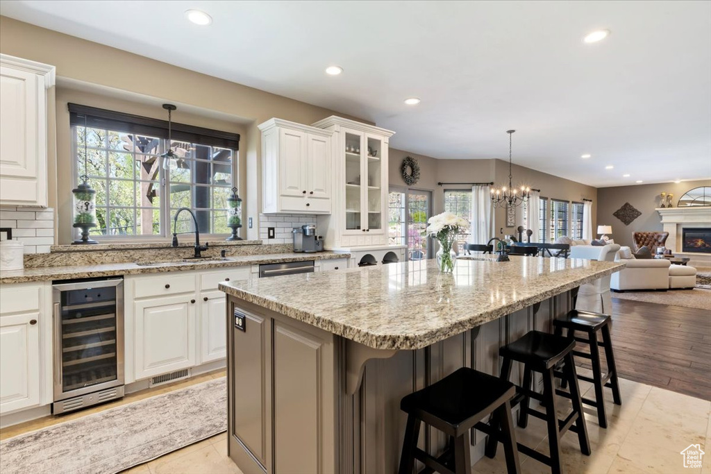 Kitchen with wine cooler, a breakfast bar area, backsplash, and a sink